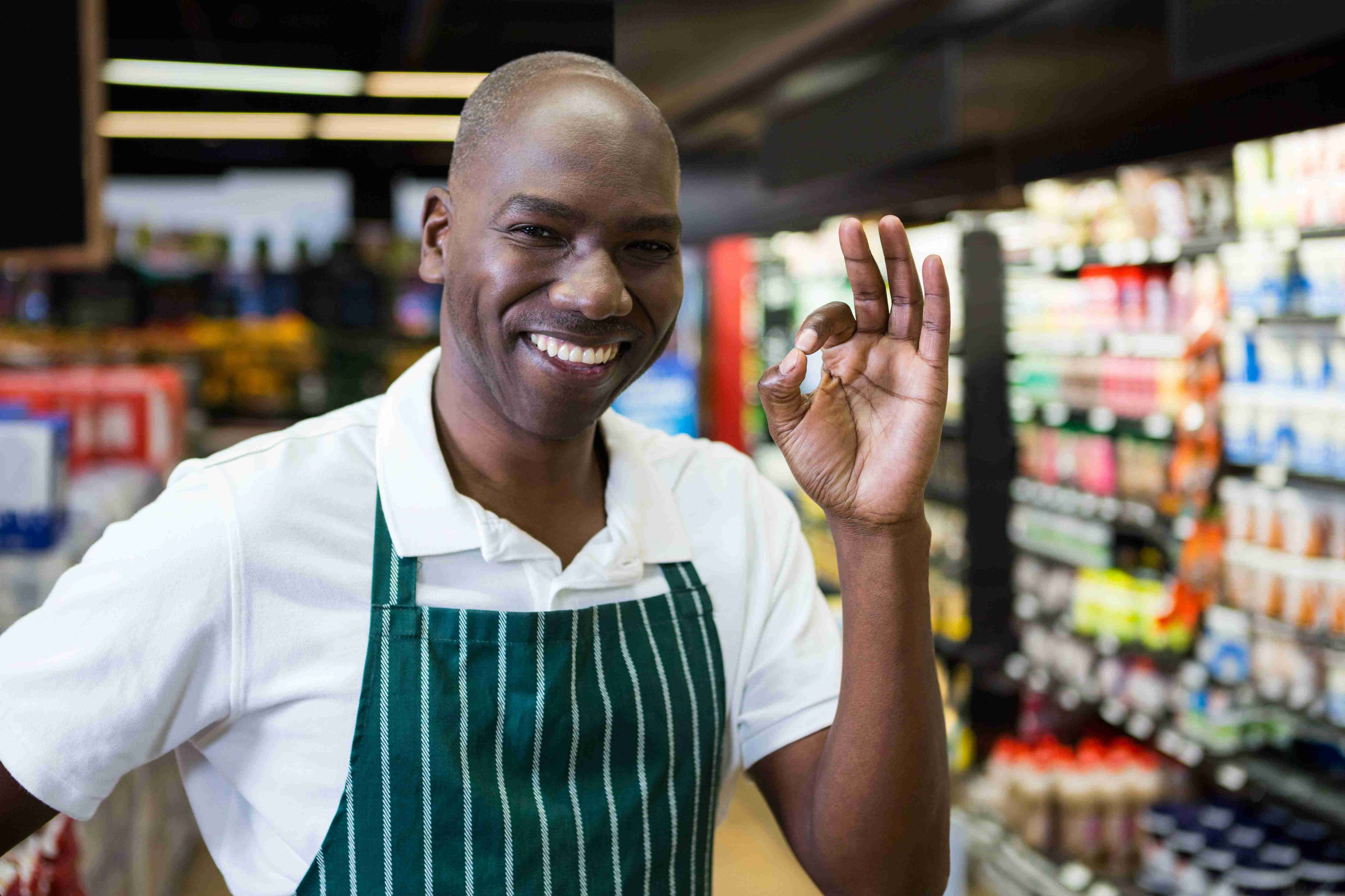 African american man wearing apron giving ok gestu