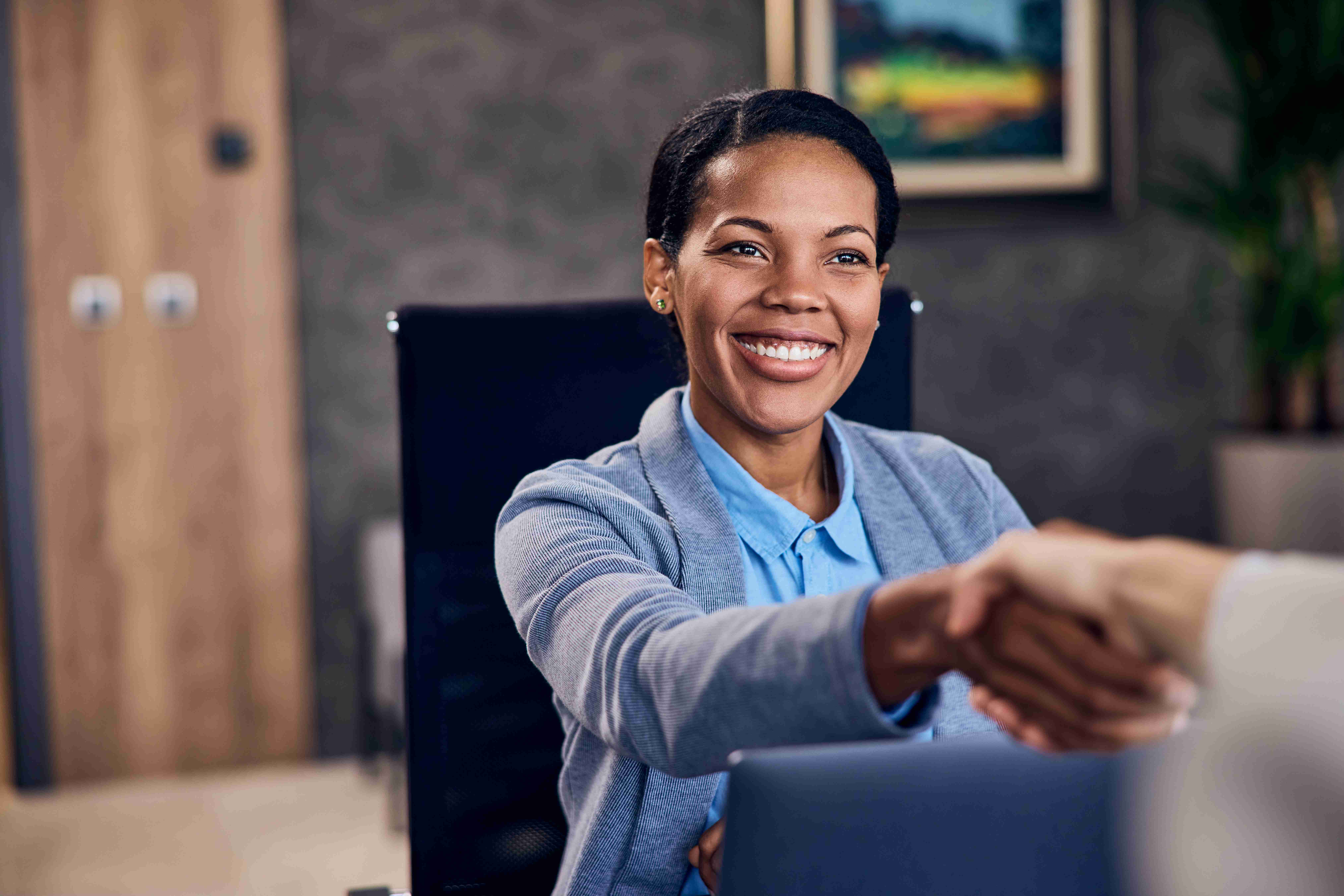 Photo of a smiling african woman shaking hands wit